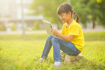 Cute little girl playing  with laptop in the park. Which increases the development and enhances outside the classroom  learning skills concept.