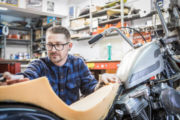 Male hipster creating motorcycle seat in workshop