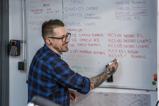 Cheerful man writing on whiteboard in workshop