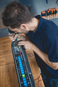 Mechanic checking electric scooter with multimeter