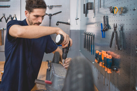 Mechanic with electric screwdriver fixing scooter