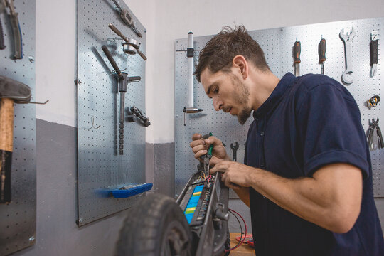 Mechanic checking electric scooter with multimeter