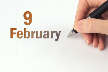 February 9th. Day 9 of month, Calendar date. The hand holds a black pen and writes the calendar...