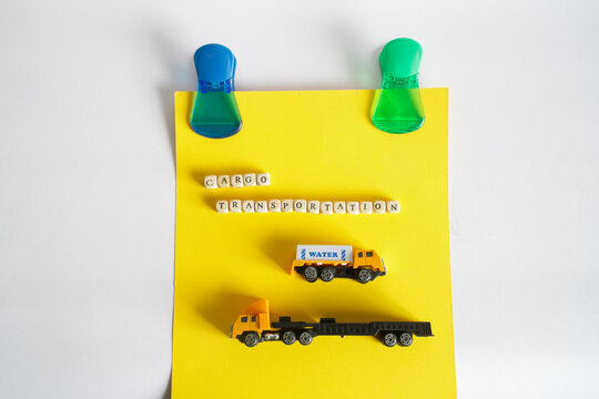 An advertisement for trucking services hangs on magnetic clips on a white bulletin board. Toy trucks and lettering cargo transportation