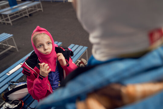 Young Man Putting On Ski Face Mask Near Kid