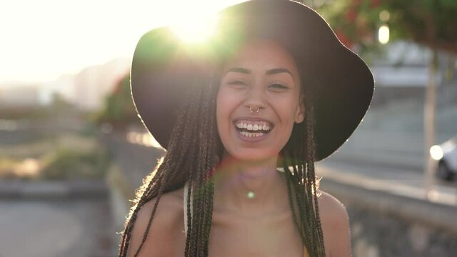 Young mixed race woman smiling in camera outdoor with sunset in the background
