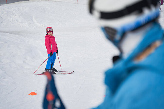 Unrecognizable parent and kid skiing on snowy hill slope
