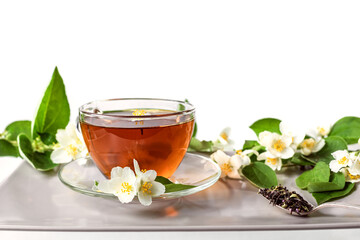 A cup of green jasmine tea on a ceramic tray, decorated with branches and flowers of jasmine. White background, copyspace