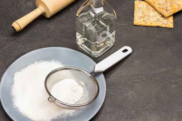 Flour and sieve on gray plate.