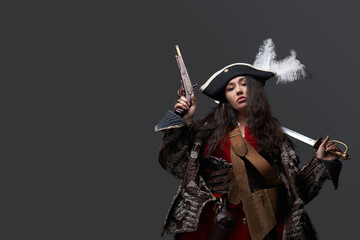 Female model dressed like pirate with saber and gun