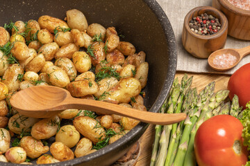 Close-up of young, baby potatoes fried in a pan with garlic and herbs. Top view. Homemade food.