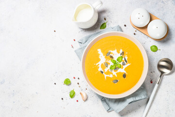 Traditionl Pumpkin soup puree with cream. Top view image at white table.
