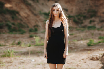 Portrait of a young beautiful woman in a black dress walks outdoor