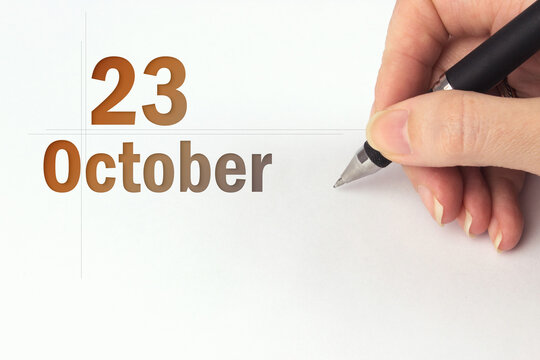 October 23rd. Day 23 of month, Calendar date. The hand holds a black pen and writes the calendar date. Autumn month, day of the year concept.