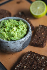 A bowl of guacamole and toast made from black grain bread