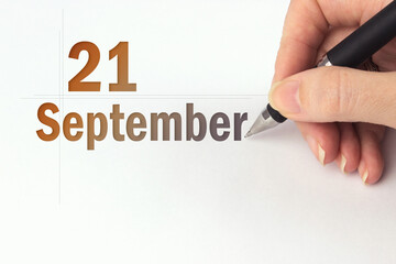 September 21st . Day 21 of month, Calendar date. The hand holds a black pen and writes the calendar date. Autumn month, day of the year concept.