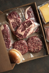 A set for a barbecue party. Raw marbled beef steaks in vacuum packaging and ingredients for burgers.