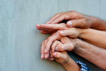 Close-up hands of people of different ages on the background of the wall, family concept