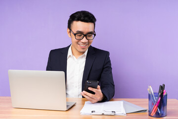 Asian businessman male portrait sitting on desk, isolated on purple background