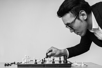 Asian businessman is thinking about his next move on the chess board