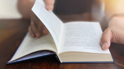 Close-up of a man sitting at a wooden table and reading a book