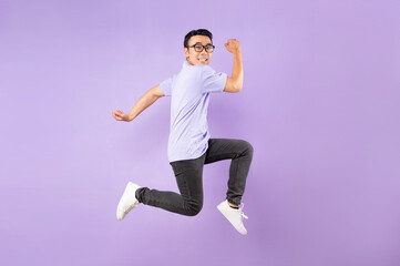 Portrait of a jumping asian man, isolated on purple background