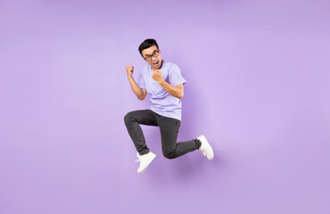 Fototapeta na wymiar Portrait of a jumping asian man, isolated on purple background