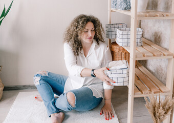 Portrait of a young woman in casual clothes beautifully putting things in containers and boxes. The...