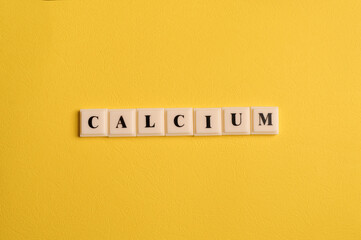 Square letters with text CALCIUM isolated on yellow background