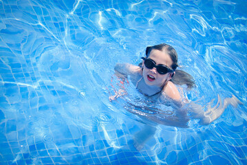Naklejka premium Active young girl swimming pool with goggles on her face