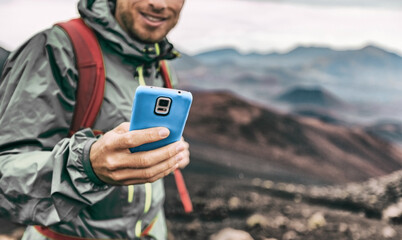 Phone man texting during trek hike in volcano mountain. Young person on travel lifestyle using his...
