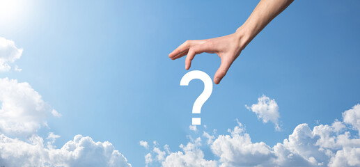 Fototapeta premium Male hand holding question mark icon on blue background.Banner with copy space. Place for text.