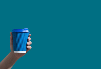 Cardboard cup of coffee or tea on a blue background with copy space. Hot drinks to go minimalistic concept