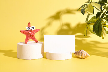 Mock up business card on pedestal with creative starfish in sunglasses against the backdrop of hard shadows of tropical plants