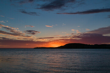 An orange and gold sunset over a body of water - Rocky Harbour, Newfoundland, Canada