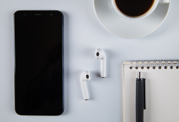 Smartphone, wireless earphones,  coffee and accessories on white  background.