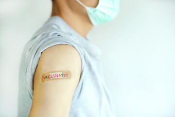 Multicolor ' VACCINATED ' write on plaster a man showing his shoulder that received vaccine, vaccination, increase immunization, prevention concept                                