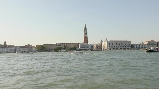 Footage from a boat in the canals of Venice. Campanile di San Marco and Palazzo Ducale in the background. Boats in the canals of Venice