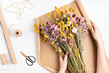 Florist composing bouquet of dry flowers and herbs