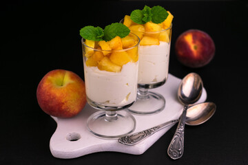 Dessert of yogurt with peach and mint on a black background.