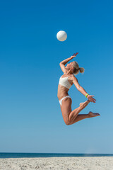 Young girl playing volleyball on the beach. Professional sport concept