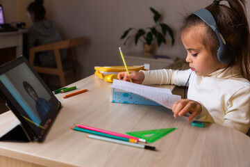 Little girl studying at home remotely via internet