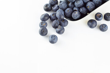 Zenith view. Blueberries in a metal scoop and scattered on the white background. Copy space.