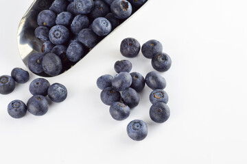 Zenith view. Blueberries in a metal scoop and scattered on the white background