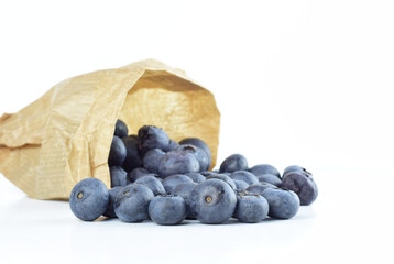 Blueberries scattered and inside kraft paper sack bag, on white background. Copy space.