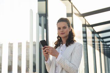 Fototapeta premium Lifestyle of A thirty-something woman. Portrait of a beautiful woman texting outdoors, smiling.