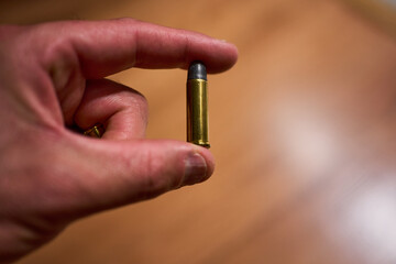 Hand holding a revolver bullet with two fingers without having been fired