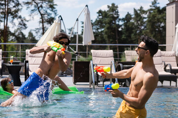 excited arabian man playing water battle game with friends in pool