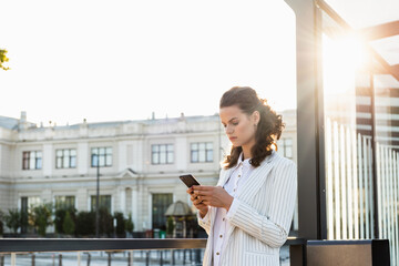 Young woman with smartphone commuting in the city, against busy city traffic and highrise buildings. Young woman with smartphone commuting in the city.