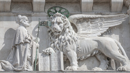 Winged lion with a Bible and a priest at Basilica San Marco in Venice, Italy, summer time, details,...